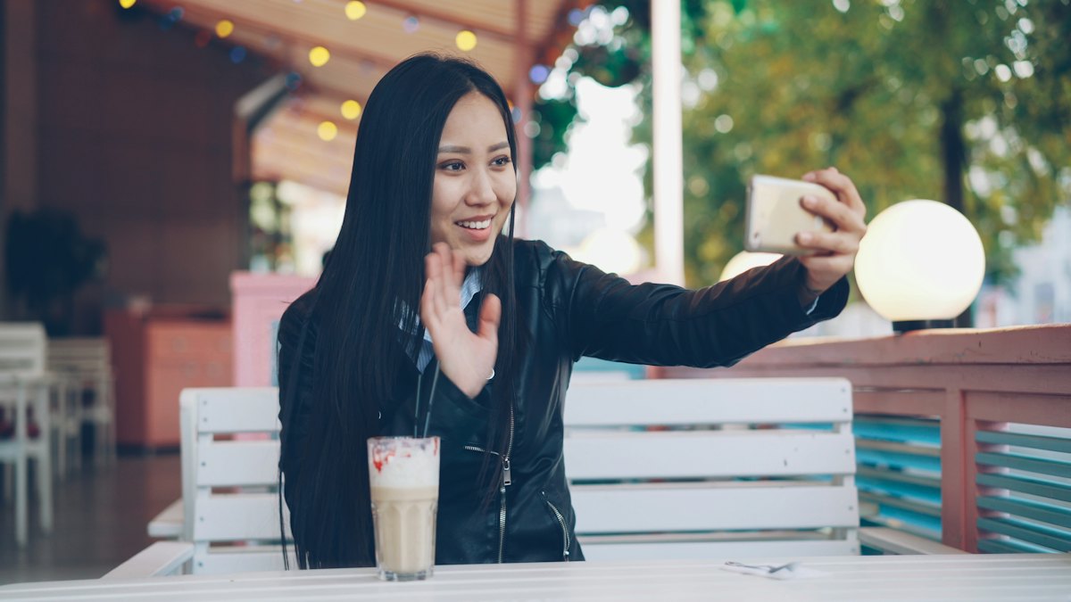 A woman smiling at her phone in an outdoor cafe