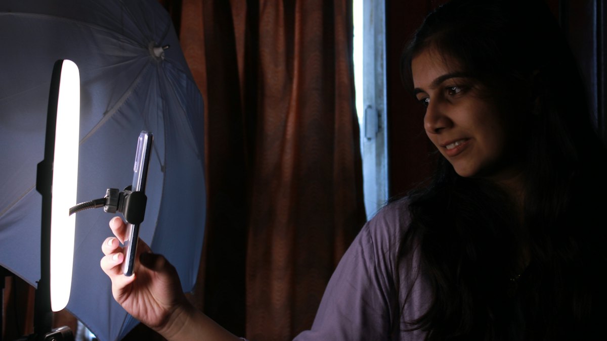 A creator holding a phone in front of a ring light